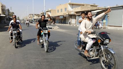 Des habitants de Tabqa (Syrie) et des militants de l'Etat islamique f&ecirc;tent la prise par les jihadistes de l'a&eacute;roport militaire de la r&eacute;gion, dimanche 24 ao&ucirc;t 2014. (REUTERS)