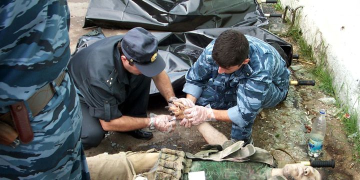 Les policiers russes prenant les empreintes de l'un des preneurs d'otages tués pendant l'assaut à Beslan, en septembre 2004. 

	  (STR News/ Reuters)