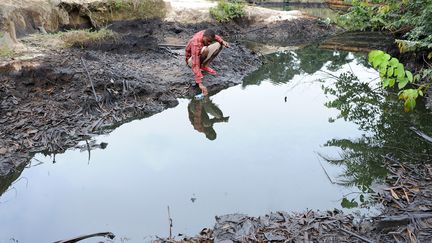 Dans cette photo d'archives prise le 11 août 2011, un homme écope du pétrole brut qui proviendrait d'une panne d'équipement Shell dans l'Ogoni, dans l'État de Rivers, au sud du Nigeria. (PIUS UTOMI EKPEI / AFP)