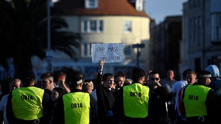 Des policiers de dos lors d'une manifestation d'extrême droite à Weymouth (Royaume-Uni), le 4 août 2024. (JUSTIN TALLIS / AFP)