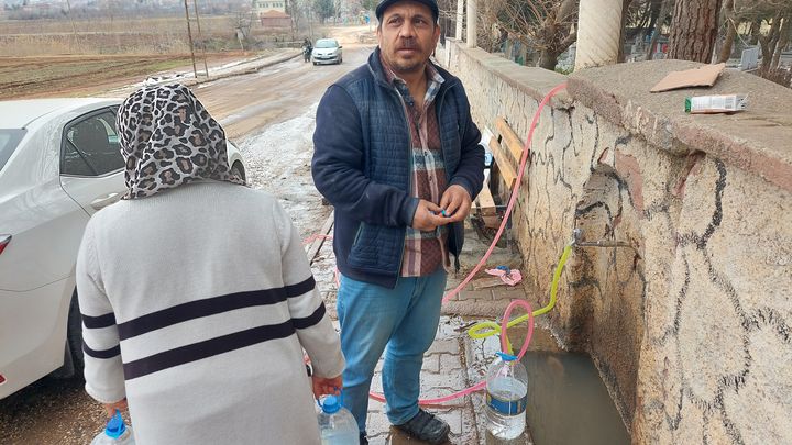 Akif et Ayse remplissent leurs bidons à l'un des seuls robinets de la ville qui fonctionne encore, à Golbasi, en Turquie, le 21 février 2023. (JULIE PIETRI / RADIO FRANCE)