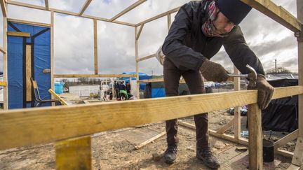 Un migrants contruit un abri dans la "jungle" de Calais, près de la zone dans laquelle ont été installée des conteneurs, le 15 février 2016.&nbsp; (MAXPPP)