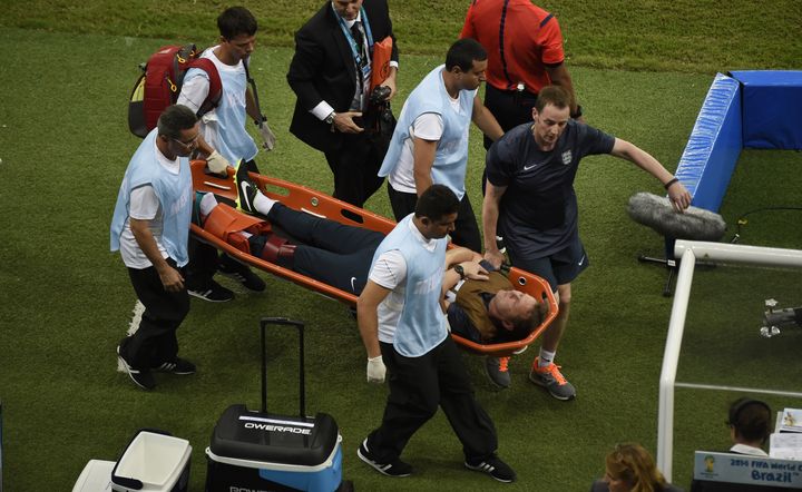 Le pr&eacute;parateur anglais&nbsp;Gary Lewin est &eacute;vacu&eacute; en civi&egrave;re apr&egrave;s s'&ecirc;tre cass&eacute; la cheville en c&eacute;l&eacute;brant le but anglais face &agrave; l'Angleterre, samedi 14 juin &agrave; Manaus (Br&eacute;sil). (ODD ANDERSEN / AFP)