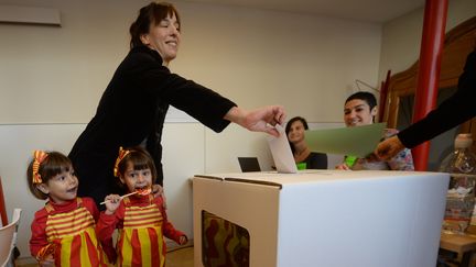 Une femme, accompagn&eacute;e de ses filles habill&eacute;es aux couleurs de la Catalogne, participe au processus participatif sur l'ind&eacute;pendance de la Catalogne, dimanche 9 novembre, &agrave; Barcelone (Espagne).&nbsp; (EVRIM AYDIN / ANADOLU AGENCY / AFP)
