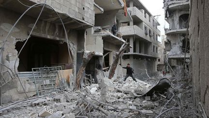 Un jeune Syrien examine le site bombardé d'Hamouria, dans la région de la Ghouta orientale (Syrie), le 22 février 2018. (ABDULMONAM EASSA / AFP)