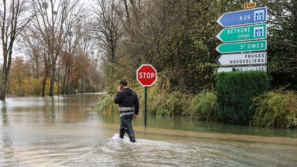 Un habitant de Neuville-sous-Montreuil (Pas-de-Calais) marche dans une rue inondée, le 13 novembre 2022. (DENIS CHARLET / AFP)