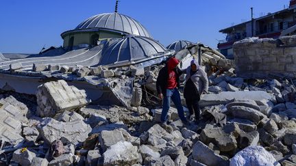 Des habitants de Hatay, en Turquie, sur les ruines d'un bâtiments, le 10 février 2023. (YASIN AKGUL / AFP)