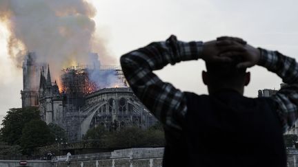 Les passants s'arrêtent, sidérés et impuissants, en voyant le monument le plus visité d'Europe prendre feu.&nbsp; (GEOFFROY VAN DER HASSELT / AFP)