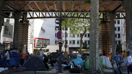 Des migrants installés dans un campement sous le métro aérien dans le 19e arrondissement de Paris. (MATTHIEU ALEXANDRE / AFP)