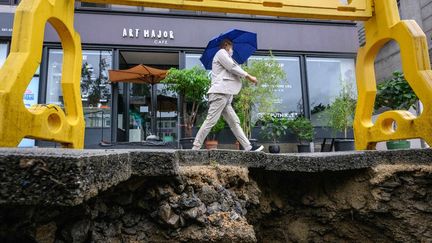 Un homme passe près d'une route effondrée à Séoul (Corée du Sud), le 9 août 2022. (ANTHONY WALLACE / AFP)