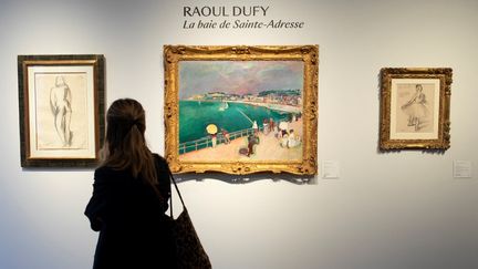 Une visiteuse devant le tableau de Raoul Dufy "La Baie de Sainte-Adresse", clou de la vente aux enchères de la collection Alain Delon, à la maison de vente Bonhams-Cornette de Saint Cyr du 22 juin 2023, parti à 1 016 400 euros. (IAN LANGSDON / AFP)