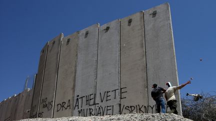 Des Palestiniens jettent des pierres en direction de soldats isra&eacute;liens, lors d'une manifestation contre la construction du mur de s&eacute;paration dans le village de Nilin, le 1er juin 2012.&nbsp; (ABBAS MOMANI / AFP)