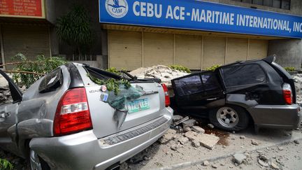 Des voitures d&eacute;truites par des d&eacute;bris dans ville de Cebu (Philippines), apr&egrave;s un tremblement de terre, le 15 octobre 2013. (STR / AFP)