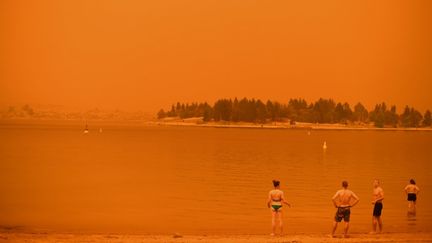 L'année 2020 commence&nbsp;avec des images apocalyptiques. Des feux d'ampleur exceptionnelle ont ravagé&nbsp;plus de 10 millions d'hectares de végétation en Australie. Ici, des habitants de Jindabyne (Nouvelle-Galles du Sud) se rafraîchissent dans un lac sous un ciel rougi par les fumées, le 4 janvier 2020. (SAEED KHAN / AFP)