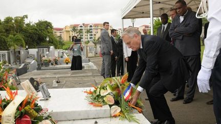 Le Premier ministre Jean-Marc Ayrault dépose une gerbe sur la tombe d'Aimé Cesaire, au cimetière La Joyaux de Fort-de-France (Martinique), le 26 juin 2013, en présence de Jacques Cesaire, fils du poète et homme politique décédé en 2009
 (JEAN-MICHEL ANDRE / AFP)