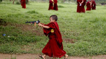 Un jeune apprenti moine bouddhiste joue avec une arme en plastique lors d'une r&eacute;cr&eacute;ation au monast&egrave;re&nbsp;Gyudmed Tantric &agrave; Gurupura (Inde), le 15 juillet 2013. (AIJAZ RAHI / AP / SIPA)