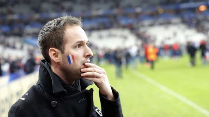 Un supporter français se fige sur la pelouse du Stade de France en apprenant que des attaques ont frappé la région parisienne. (CHRISTOPHE ENA/AP/SIPA / AP)