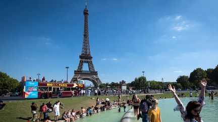 Des touristes plongent dans la fontaine du Trocadéro, le 2 août 2018, à Paris.&nbsp; (GERARD JULIEN / AFP)