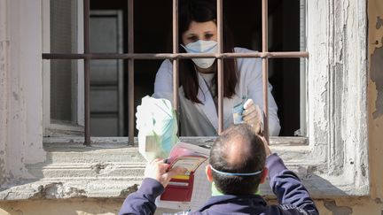 Une pharmacienne confinée de Castiglione d'Adda en Italie vend les médicaments par la fenêtre de l'officine. (PHILIPPE DE POULPIQUET / MAXPPP)