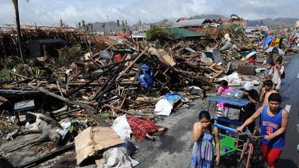 Des habitants de Tacloban (Philippines) marchent au milieu des ruines, le 10 novembre 2013. (TED ALJIBE / AFP)