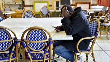 Un&nbsp;migrant soudanais regarde son téléphone portable dans un centre d'accueil et d'orientation, le 4 janvier 2017 à Saint-Brevin-les-Pins&nbsp;(Loire-Atlantique). (LOIC VENANCE / AFP)