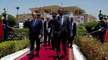 Fran&ccedil;ois Hollande marche aux c&ocirc;t&eacute;s du pr&eacute;sident tchadien Idriss Deby&nbsp;&agrave; N'Djamena le 19 juillet 2014, lors de la derni&egrave;re &eacute;tape du voyage pr&eacute;sidentiel en Afrique de l'Ouest. (ALAIN JOCARD / POOL / AFP)