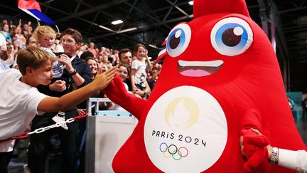 Une mascotte Phryge des Jeux de Paris 2024 salue un spectateur du match de handball Croatie-Japon, à l'Arena Paris-Sud de la Porte de Versailles, le 27 juillet 2024. (CHRISTIAN PETERSEN / GETTY IMAGES EUROPE)