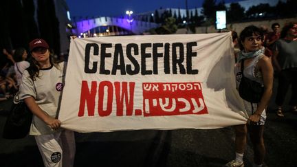 Deux manifestantes brandissant une banderole "un cessez-le-feu maintenant", lors d'un rassemblement devant la Knesset, lundi 17 juin à Jérusalem. (SAEED QAQ / ANADOLU)