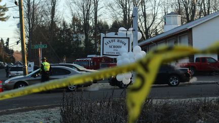 Devant l'école primaire Sandy Hook de Newton (Etats-Unis), le 15 décembre 2012, au lendemain de la fusillade qui a tué 20 enfants et six adultes. (SPENCER PLATT / GETTY IMAGES NORTH AMERICA via AFP)