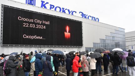 Des personnes en deuil font la queue pour déposer des fleurs devant un mémorial de fortune devant l'hôtel de ville de Crocus, à Krasnogorsk, près de Moscou, le 24 mars 2024, alors que la Russie célèbre une journée nationale de deuil après un massacre qui a tué plus de 130 personnes. (OLGA MALTSEVA / AFP)