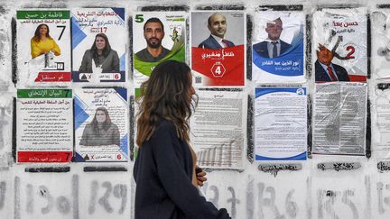 Une jeune fille passe devant des affiches électorales pour les élections législatives, à Tunis, le 14 décembre 2022. (FETHI BELAID / AFP)