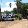 Une femme se tient devant des voitures incendiées lors de violences entre bandes, le 21 novembre 2022, à Mamoudzou (Mayotte). (GREGOIRE MEROT / AFP)