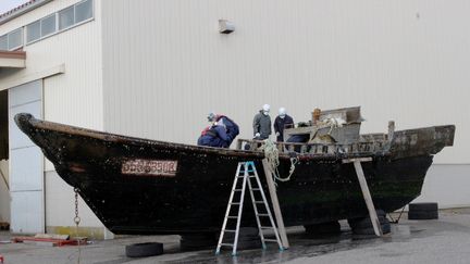 Des gardes-côtes japonais photographiés le 24 novembre 2015, en train d'examiner un des bateaux en bois transportant des cadavres, retrouvé au large des côtes de l'archipel. (AFP)