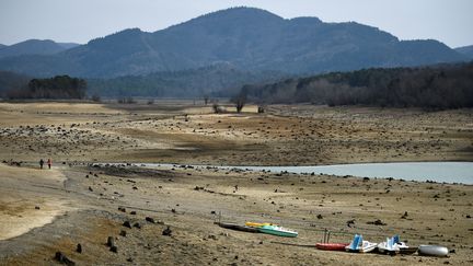 Deux personnes marchent près du lac de Montbel, quasiment à sec, le 21 février 2023, dans l'Ariège. (VALENTINE CHAPUIS / AFP)