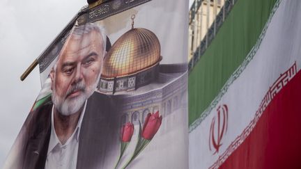 Une bannière à l'effigie d'Ismaïl Haniyeh, le chef du Hamas tué fin juillet, flotte à côté d'un drapeau iranien lors de son enterrement à Téhéran, en Iran, le 1er août 2024. (MORTEZA NIKOUBAZL / NURPHOTO / AFP)