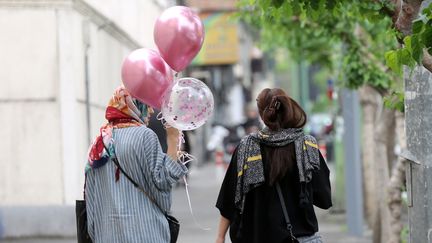 Deux femmes, l'une portant le voile, l'autre non, marchent dans une rue de Téhéran, le 13 avril 2023. (FATEMEH BAHRAMI / ANADOLU AGENCY / AFP)