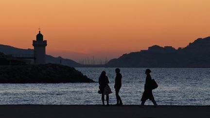 Des passants sur le front de mer à Marseille, le 16 décembre 2021. (NICOLAS TUCAT / AFP)