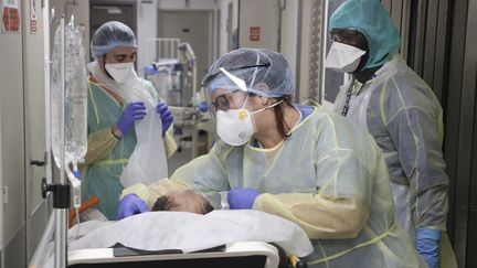 Des soignants autour d'un patient atteint du Covid-19, dans une clinique de Bagnolet, le 8 avril 2020. (LUDOVIC MARIN / AFP)