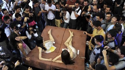 Des visiteurs et journalistes prennent en photo des hotesses faisant la promotion de matelas lors d'un salon automobile &agrave; Hefei (Chine), le 1er octobre 2013. (JIANAN YU / REUTERS)