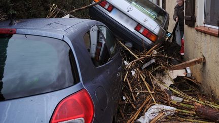 Une femme tente de passer la porte de sa maison obstru&eacute;e par des v&eacute;hicules et des d&eacute;bris amoncel&eacute;es par les inondations &agrave; La Londe-les-Maures (Var), le 20 janvier 2014. (BORIS HORVAT / AFP)