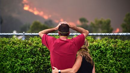 Un couple regarde les flammes se rapprocher de leur maison, le 9 août 2018 à Lake Elsinore (Etats-Unis). (ROBYN BECK / AFP)