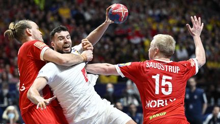 Le joueur de l'équipe de France de handball Nedim Remili tente de tirer face à deux défenseurs danois en finale du Mondial, à Stockholm (Suède), le 29 janvier 2023. (JESSICA GOW / TT NEWS AGENCY / AFP)