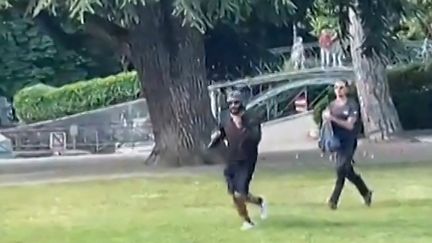 Une capture d'écran d'une vidéo amateur de l'attaque au couteau à Annecy (Haute-Savoie), montrant un passant armé d'un sac à dos poursuivre l'assaillant, le 8 juin 2023. (AFPTV)