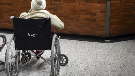 Une personne âgée en fauteuil roulant devant un mur. (RAUL ARBOLEDA / AFP)