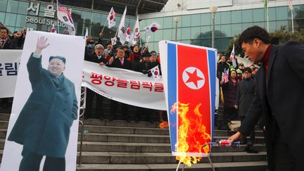 Des manifestants sud-coréens brûlent un drapeau nord-coréen à côté d'une photo de Kim Jong-Un lors d'un rassemblement anti-nord-coréen à Séoul le 22 janvier 2018. (- / YONHAP)