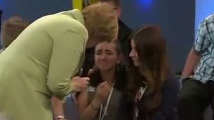 La chanceli&egrave;re allemande, Angela Merkel,&nbsp;tente de consoler la jeune&nbsp;Reem (au centre), lors d'une rencontre avec&nbsp;des adolescents, &agrave; Rostock (Allemagne), le 15 juillet 2015. ( YOUTUBE)