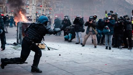 Place de la République, devant un mur de photographes, un gendarme lance une grenade lacrymogène, lors d'une manifestation de "gilets jaunes" à Paris, le 2 février 2019. (KARINE PIERRE / HANS LUCAS / AFP)