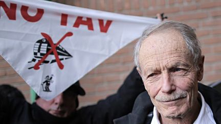 L'écrivain Erri  De Luca avec en arrière plan un manifestant contre la ligne à grande vitesse Lyon-Turin
 (MARCO BERTORELLO / AFP)