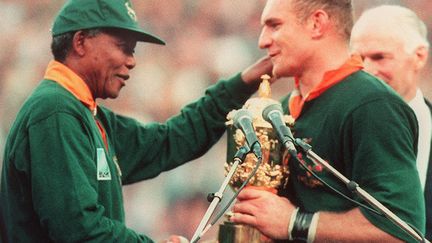 Avec l'abolition de la peine de mort et la mise en place de la Commission v&eacute;rit&eacute; et r&eacute;conciliation pour clore le chapitre de l'appartheid, la victoire de l'Afrique du Sud en coupe du monde de rugby en 1995 est l'un des moments forts de la pr&eacute;sidence Mandela. Cette &eacute;pop&eacute;e inspirera le film Invictus, de Clint Eastwood. (JEAN-PIERRE MULLER / AFP)