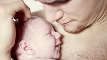 Un nourrisson dans les bras d'un jeune père. (ANNE-SOPHIE BOST / MAXPPP)